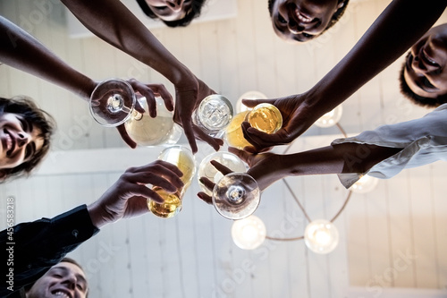 Group of friends making a toast, upward view of hands holding glasses
