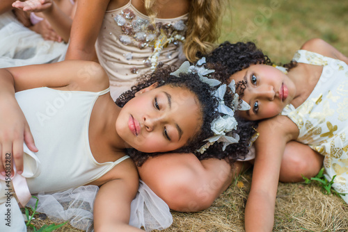 Group of young girls, dressed as fairies, lying on grass photo