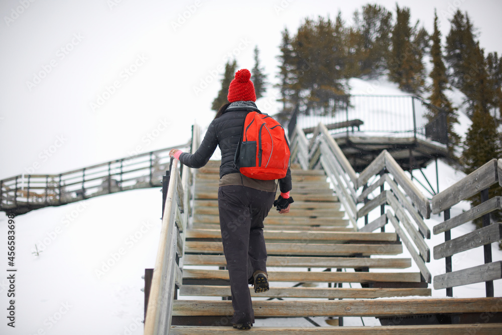 Hiker ascending stairs on snow covered landscape, Banff, Canada