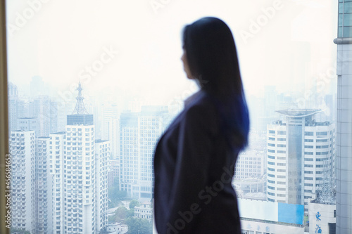Rear view of businesswoman looking through window at cityscape