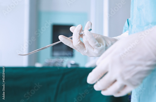 Fotografi Hands of surgeon wearing surgical gloves holding surgical instrument in maternit