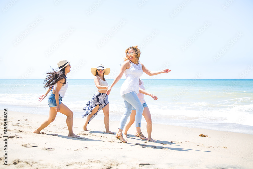 Four adult female friends fooling around on beach, Malibu, California, USA Four adult female friends fooling around on beach, Malibu, California, USA
