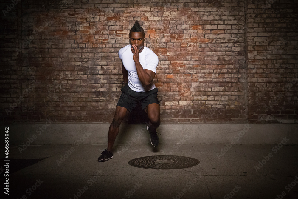 Young man with mohawk, exercising at night, in urban setting Young man with mohawk, exercising at night, in urban setting