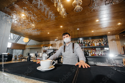 Submission of a Barista in a mask of delicious organic coffee in modern cafe during the pandemic.