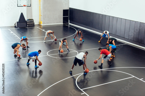 Male trainer and basketball team practicing on court