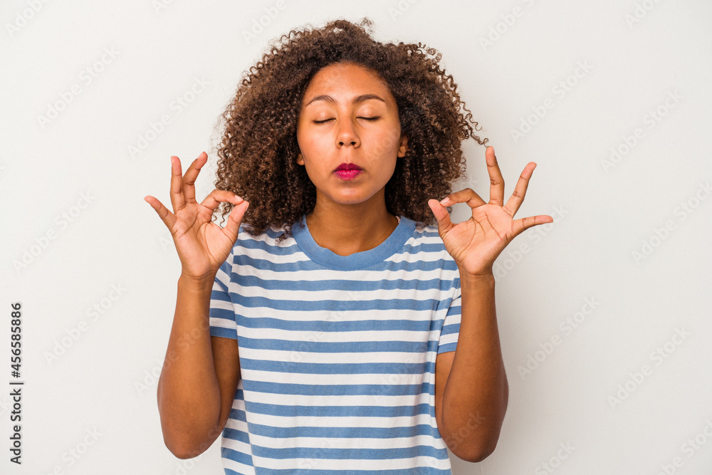 Young african american woman with curly hair isolated on white background relaxes after hard working day, she is performing yoga. Young african american woman with curly hair isolated on white background relaxes after hard working day, she is performing yoga.