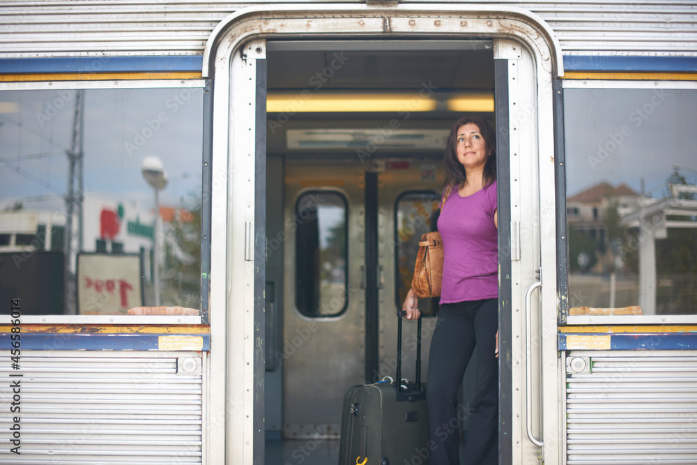 Mature woman looking out from train doorway on platform
