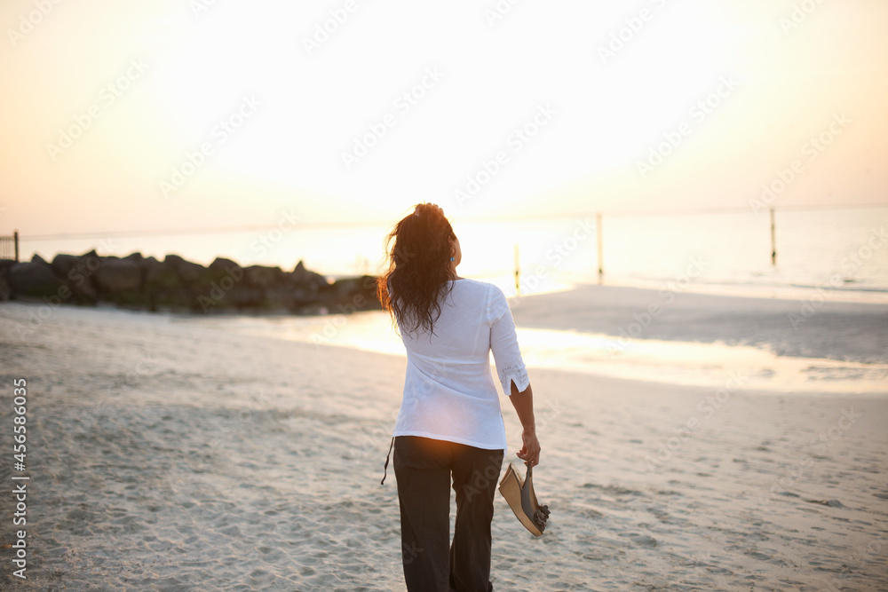 Rear view of woman strolling on beach, Dubai, United Arab Emirates Rear view of woman strolling on beach, Dubai, United Arab Emirates