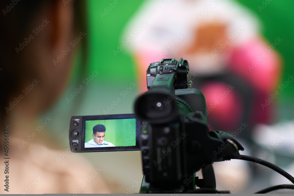 Over shoulder view of college students practicing in TV studio with green screen