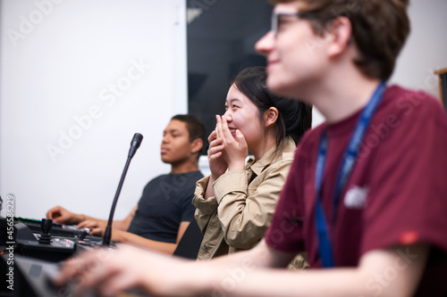 Fototapeta Young male and female college students at mixing desk in TV studio