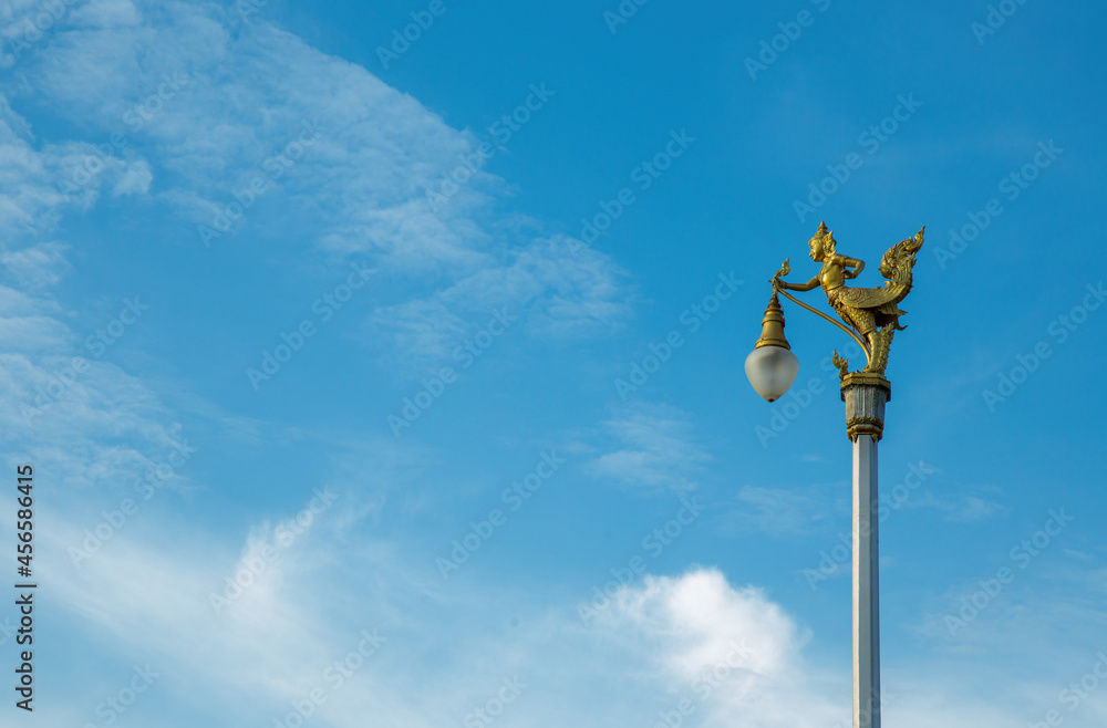Golden Kinnaree on light pole sky cloud. Lamp sculpture half-bird half-woman. Golden Kinnaree on light pole sky cloud. Lamp sculpture half-bird half-woman.