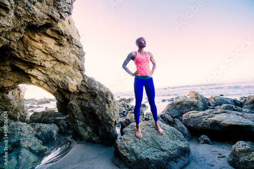 Young woman standing on rocks on beach, looking at view
