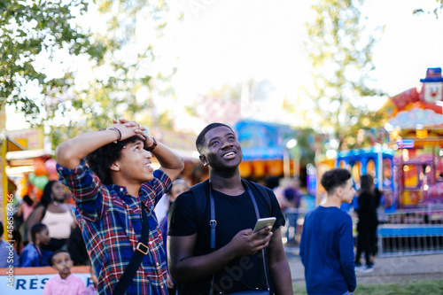 Photography Two friends at funfair, looking up, laughing