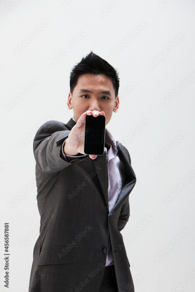 Young Asian businessman holding cellphone, studio shot Young Asian businessman holding cellphone, studio shot