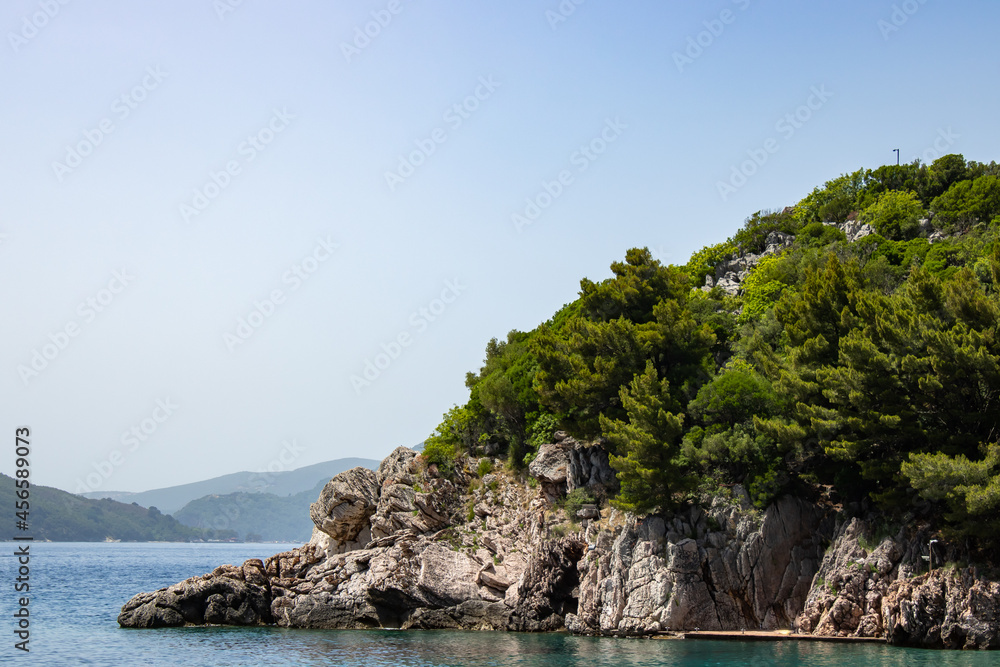 Rocky seaside coast. Boulders are standing in the beautiful water. Group of large stones against the blue sky. Big stone on the background of the sea.