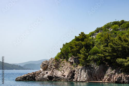 Rocky seaside coast. Boulders are standing in the beautiful water. Group of large stones against the blue sky. Big stone on the background of the sea.
