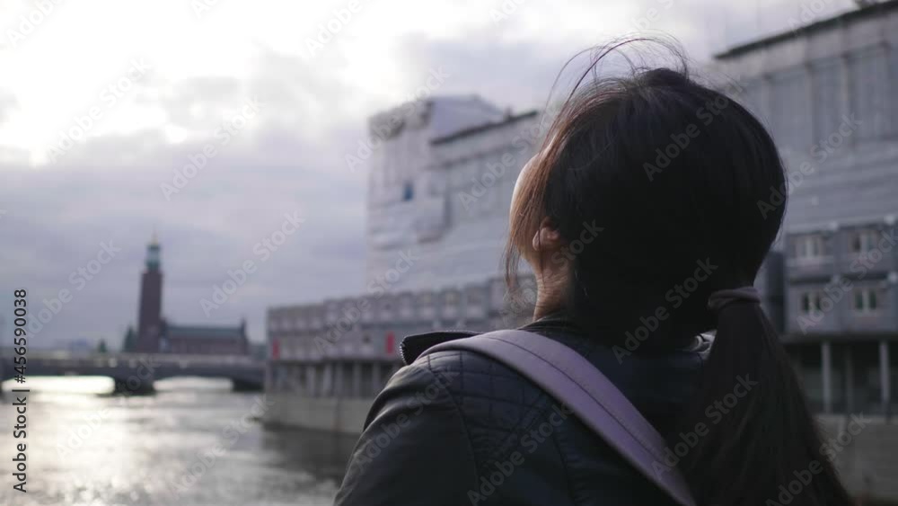 Back view of Asian woman standing and seeing beautiful view of river in Sweden, taking a deep breath and getting some fresh air, traveling abroad on holiday Back view of Asian woman standing and seeing beautiful view of river in Sweden, taking a deep breath and getting some fresh air, traveling abroad on holiday