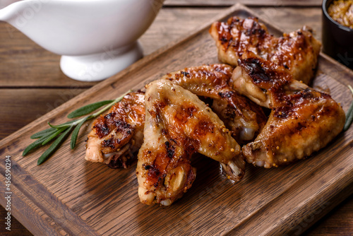 Grilled spicy chicken wings on a dark background with spices and herbs