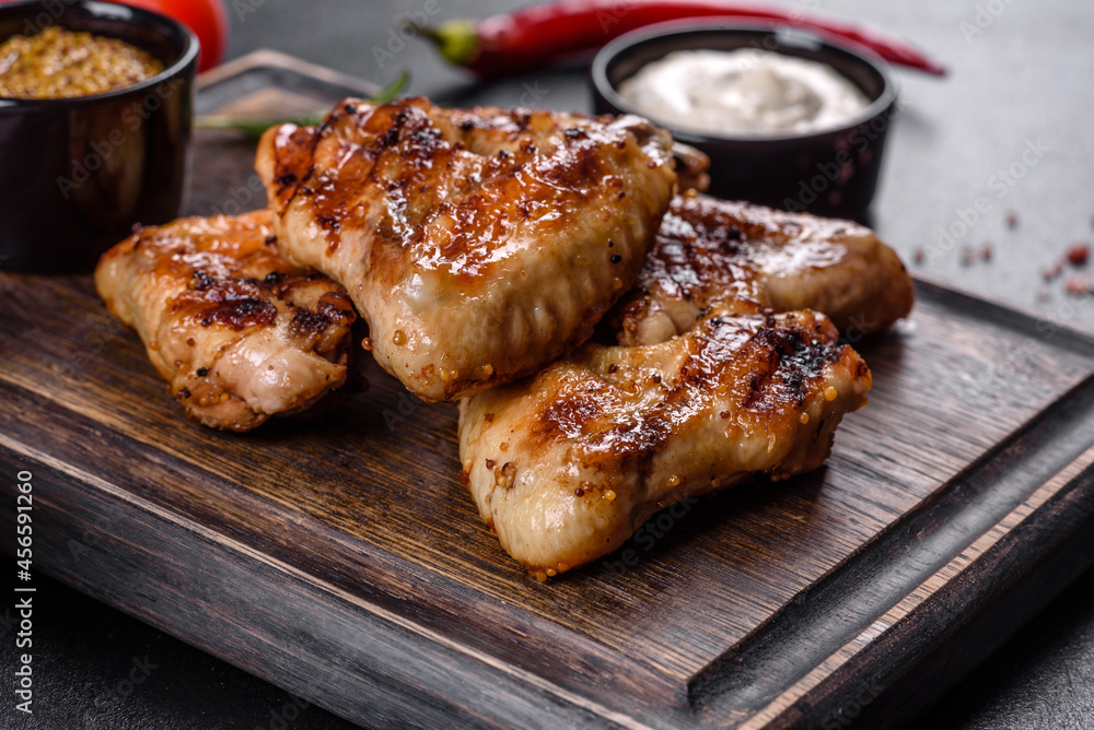 Grilled spicy chicken wings on a dark background with spices and herbs Grilled spicy chicken wings on a dark background with spices and herbs