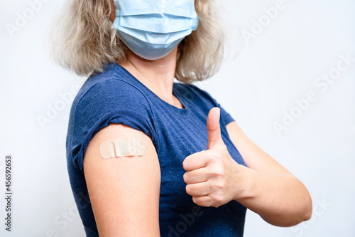 Photography Vaccinated young woman showing shoulder with plaster and thumb up