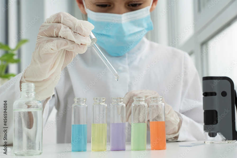 Close up image of schoolboy in protective clothers is ready for chemical experiments with liquids in different test tubes, scientific concept Close up image of schoolboy in protective clothers is ready for chemical experiments with liquids in different test tubes, scientific concept