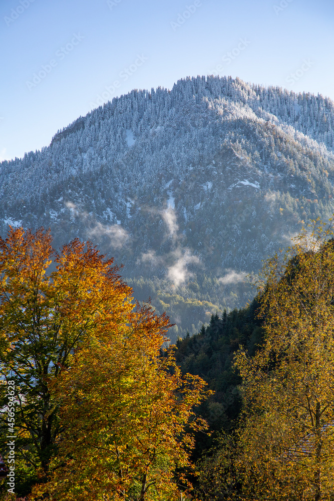 Bavarian landscape with snowy mountain and autumnal colored trees