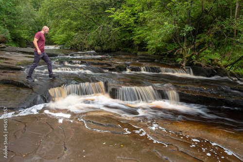 Man crossing falls at Glenbarrow river. Co. Laois, Ireland photo