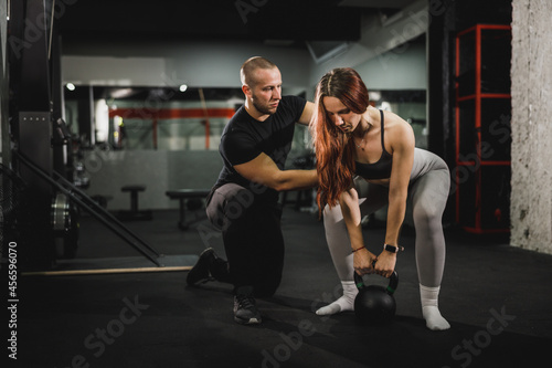 Muscular Woman Doing Kettlebell Training With Personal Trainer At The Gym