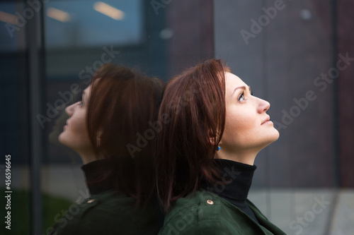 Принти на полотні A brunette woman with a bob haircut stands with her back to the mirrored wall, is reflected and looks sad