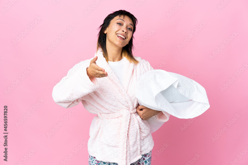 Young Uruguayan woman in pajamas over isolated pink background handshaking after good deal Young Uruguayan woman in pajamas over isolated pink background handshaking after good deal