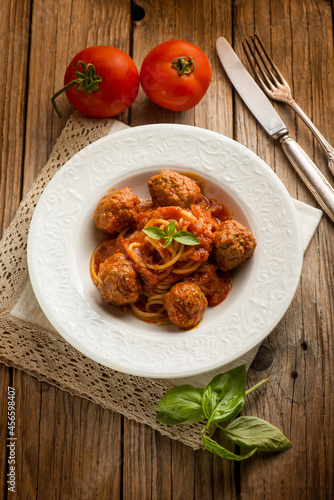 spaghetti with meatballs and tomato sauce over wooden background