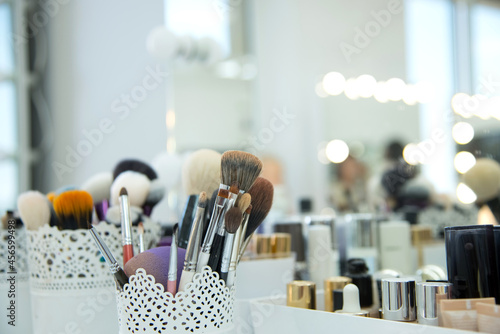 .Makeup artist table with mirror and light bulbs. Makeup brushes in the foreground. Place to insert.