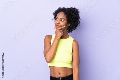 Young African American woman isolated on purple background having doubts © luismolinero