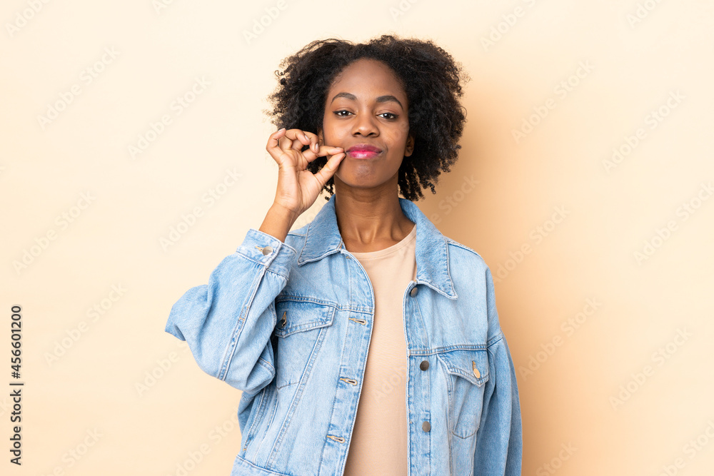 Young African American woman isolated on beige background showing a sign of silence gesture Young African American woman isolated on beige background showing a sign of silence gesture