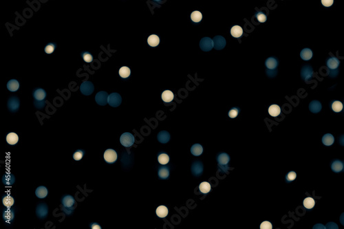 Blurred, defocused background with bokeh effect. Blue and yellow light circles on a black background
