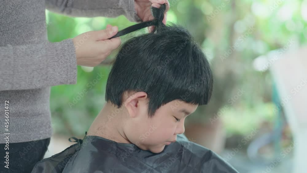 Mother tying hair to his little son by himself at home Preparing for a haircut. Asian family stay home and live during lockdown Mother tying hair to his little son by himself at home Preparing for a haircut. Asian family stay home and live during lockdown