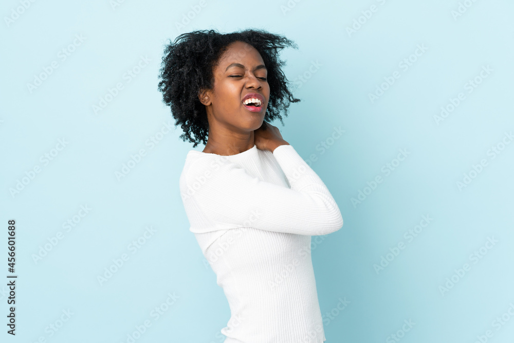 Young African American woman isolated on blue background suffering from pain in shoulder for having made an effort Young African American woman isolated on blue background suffering from pain in shoulder for having made an effort