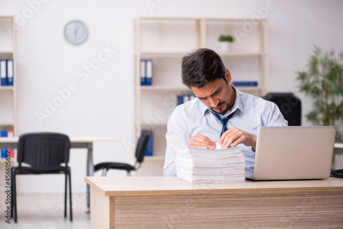 Young male employee unhappy with excessive work in the office