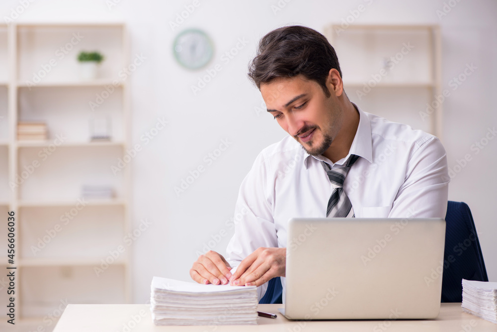 Young male employee unhappy with excessive work in the office Young male employee unhappy with excessive work in the office