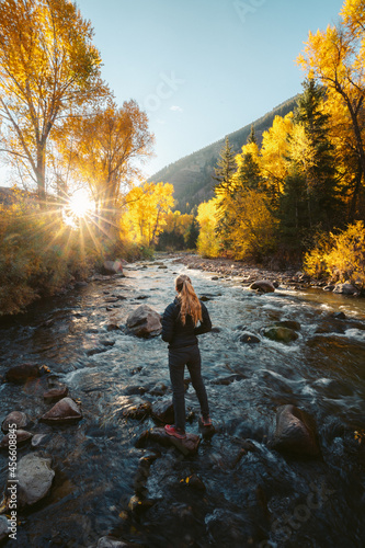 Fotografie Woman Hiker crossing river Colorado Fall Colors sunrise