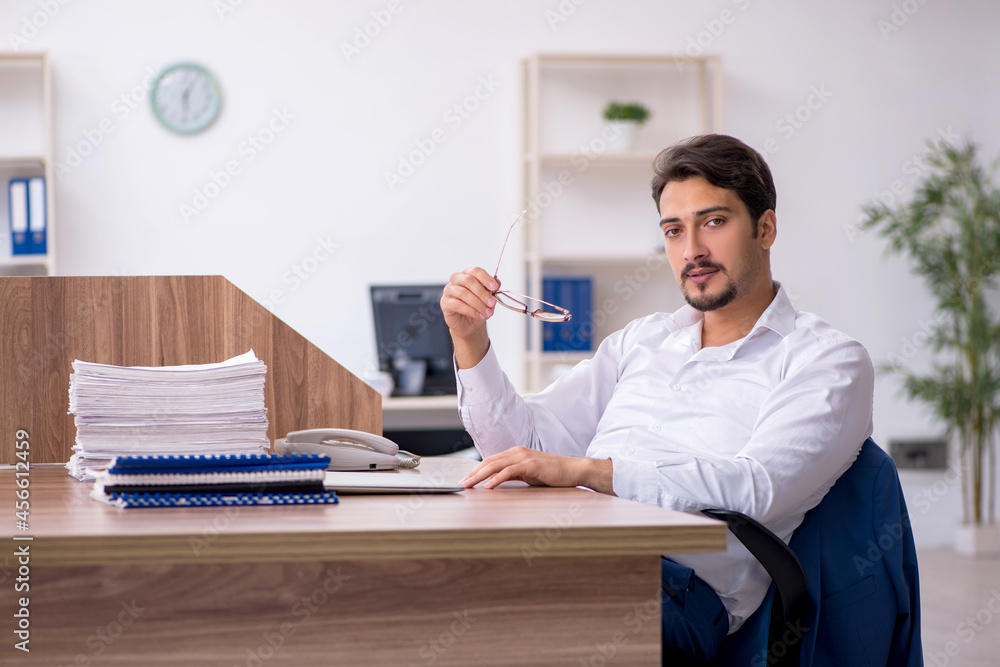 Young male employee and too much work in the office Young male employee and too much work in the office