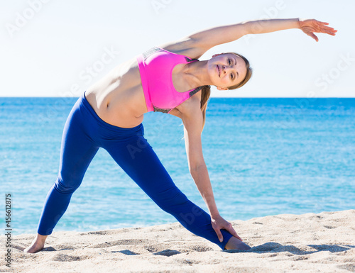 Ordinary healthy woman stretching body on the sand