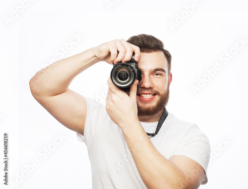 Travel, technology and life style concept: young bearded photographer taking pictures with digital camera.