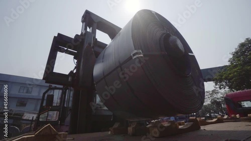 Forklift taking up a big steel roll, from a truck, in India - slow motion view photo