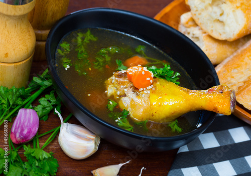 Image of delicious soup with chicken, bacon, leek and vegetables served in bowl photo