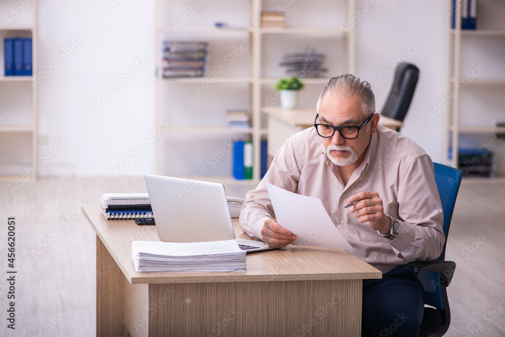 Old male employee working at workplace Old male employee working at workplace