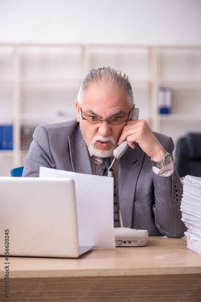 Old male employee working at workplace Old male employee working at workplace