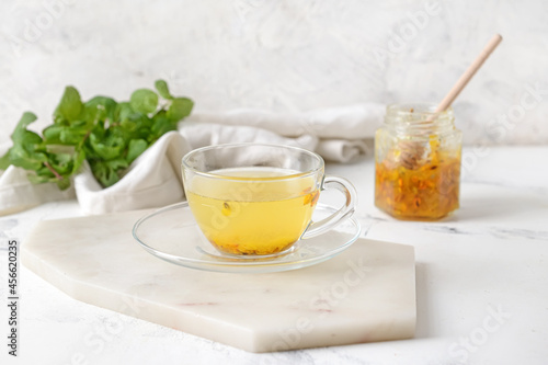 Cup of tasty tea with sea buckthorn on light background
