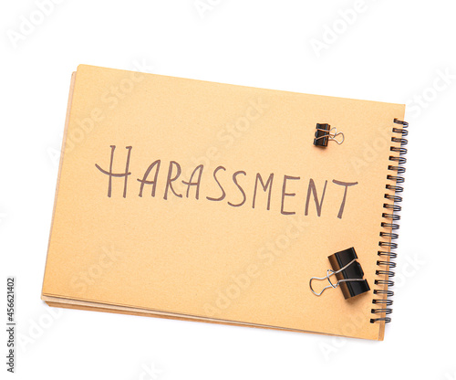 Notebook with word HARASSMENT on white background