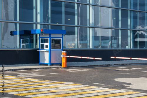 Barriers next to building. Automobile barriers. Concept is checkpoint system for cars. Yellow and white crosswalk. System of admitting cars to business center. Two automatic barriers